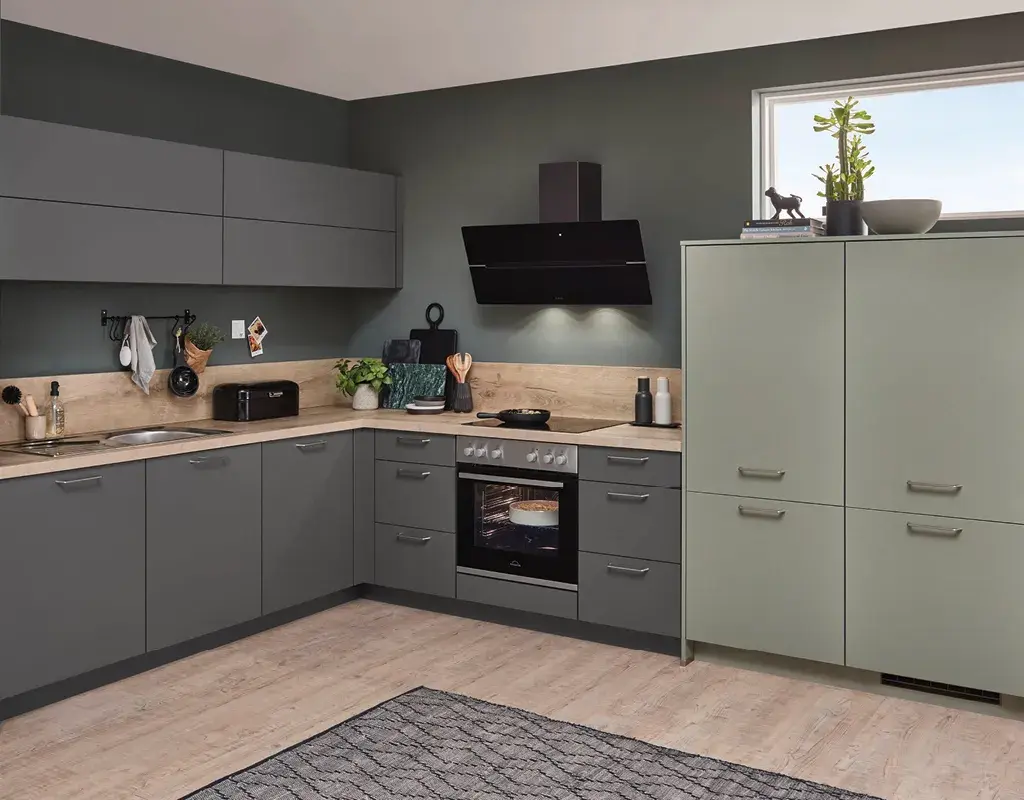 Moderne Winkelküche in Grau-Grün mit Holzarbeitsplatte, harmonischem Farbkonzept und viel Stauraum. Funktionales Küchendesign für gemütliches Wohnen und Kochen.